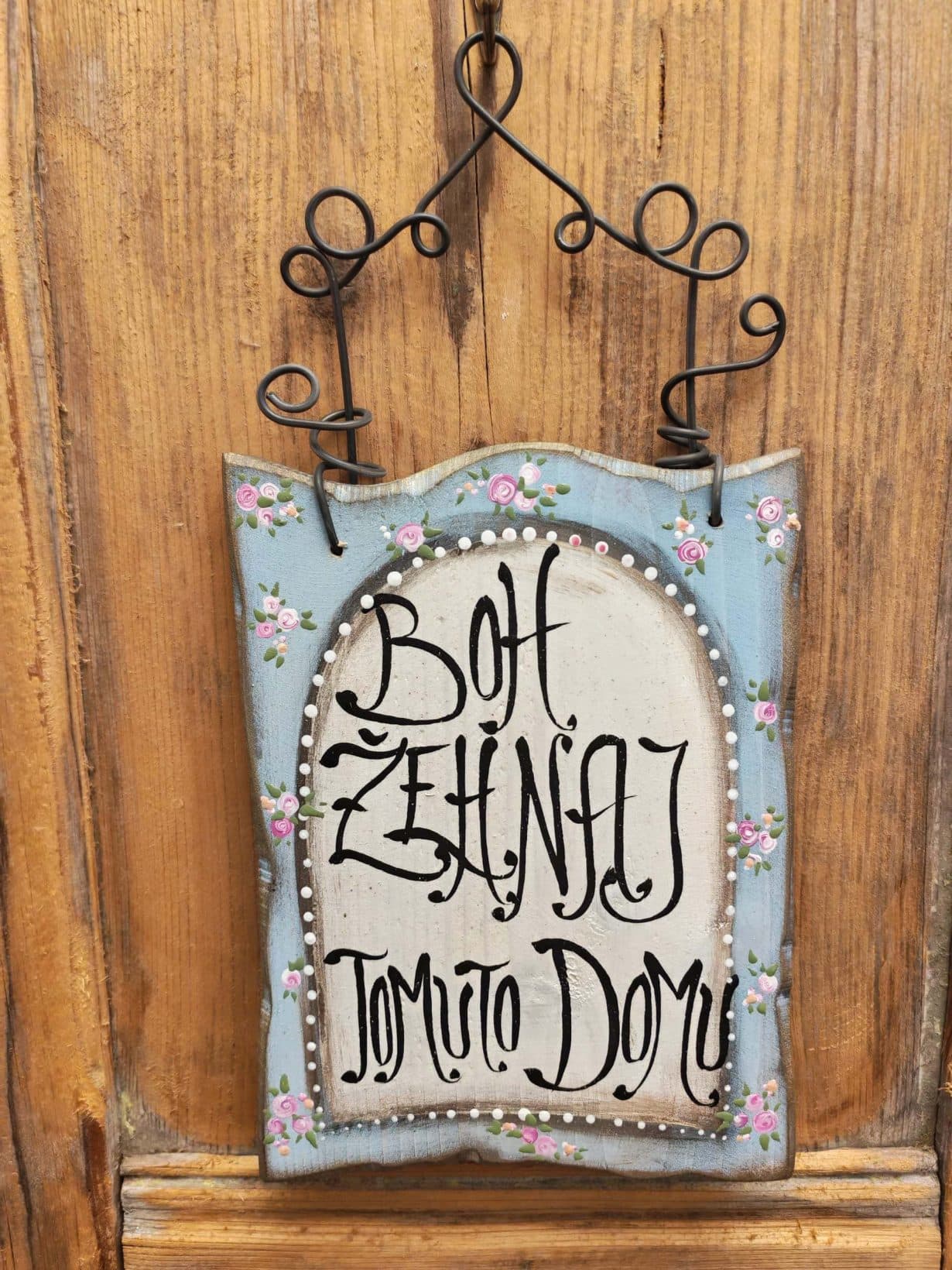 Detský domček s nápisom "Boh zhmotní Tvoje sny" na drevenom pozadí.